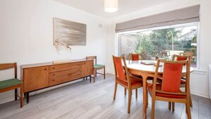 Un comedor con una mesa y sillas de madera, un banco y un armario.