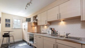 Une cuisine moderne avec des meubles de couleur bois clair, un évier en acier inoxydable et un four encastré.