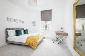 Un dormitorio moderno con cama, mesita de noche y un espejo grande.