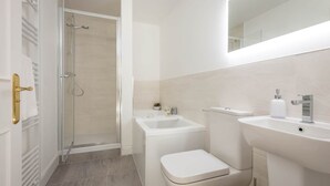 Un baño moderno con cabina de ducha de vidrio, inodoro y lavamanos.