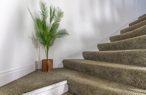 A staircase with carpeted steps and a potted plant on the landing.