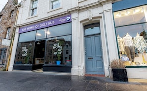 A building with a sign reading 'The Home of Golf' and a blue door.