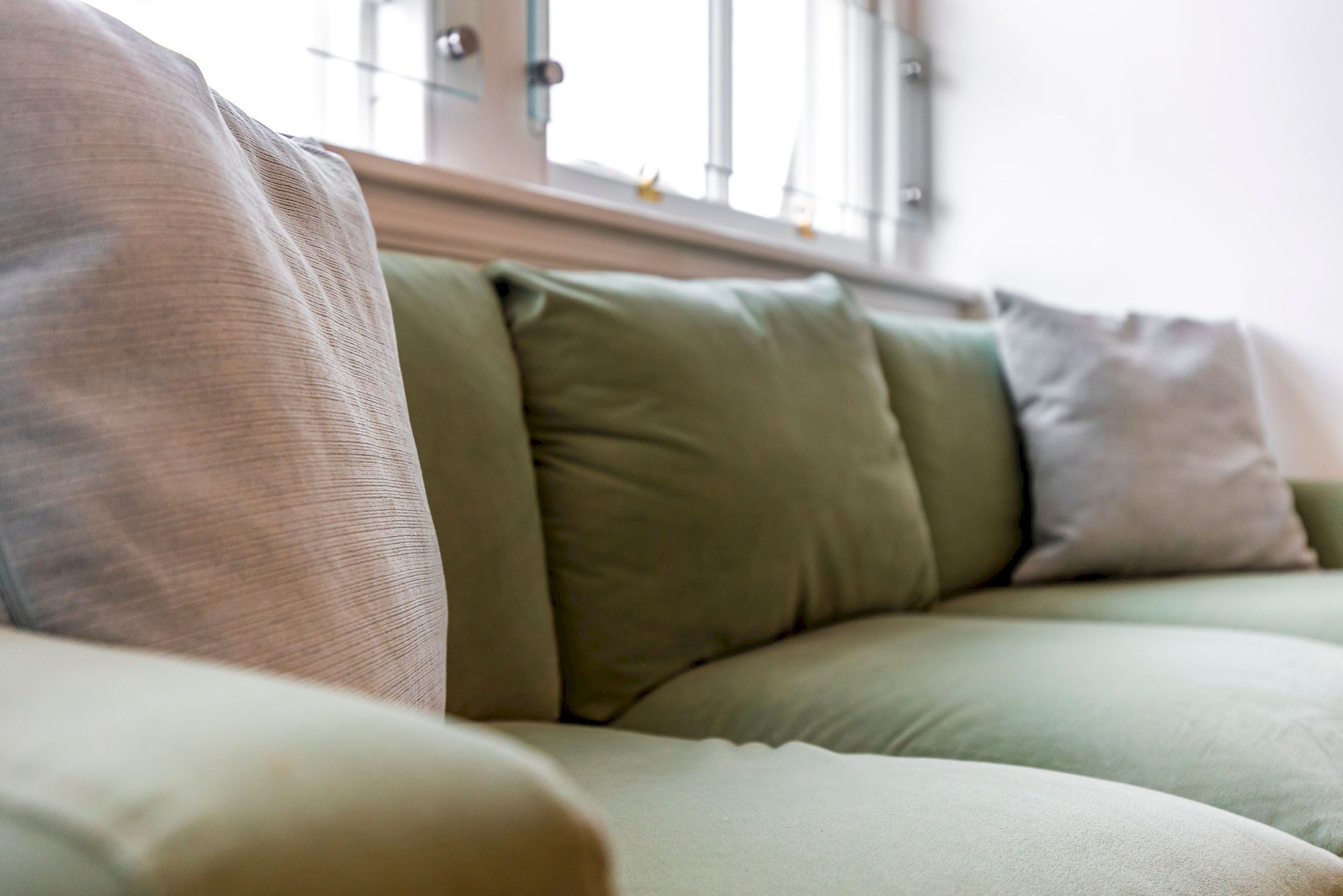 A section of a sofa with multiple cushions in different shades.