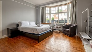 Quarto com cama, escrivaninha, cadeira e radiador.