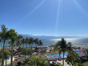 Un complexe hôtelier doté d’une piscine, de palmiers et offrant une vue sur l’océan et les montagnes.