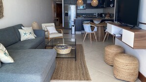 A modern living room with a grey sofa, a coffee table, and a TV on a wooden stand.