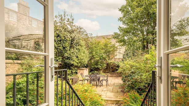 Eine Außenpatio-Terrasse mit Steinboden, umgeben von üppigem Grün und einer Steinmauer.