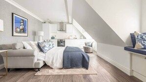 Un dormitorio con cama, escritorio y silla. Hay un cuadro en la pared y una ventana.