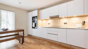 Une cuisine moderne avec des meubles blancs, un plan de travail en bois et un banc.