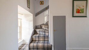 Una escalera con alfombra escocesa que lleva a una puerta.
