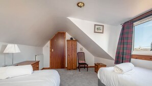 Habitación de hotel con dos camas, un armario de madera, una silla, un radiador y una ventana con vistas.