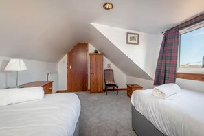 A hotel room with two beds, a wooden wardrobe, a chair, a radiator, and a window with a view. - The Cooperage | Crail (Crail)
