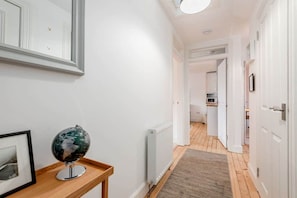 Een hal met witte muren, een wereldbol op een houten tafel, en een radiator.