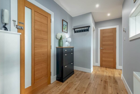 Un pasillo con suelo de madera, un mueble de almacenaje negro y dos puertas de madera.