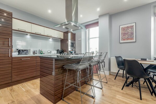 Une cuisine moderne dotée d’un îlot central, de tabourets de bar et d’un coin repas avec des chaises.