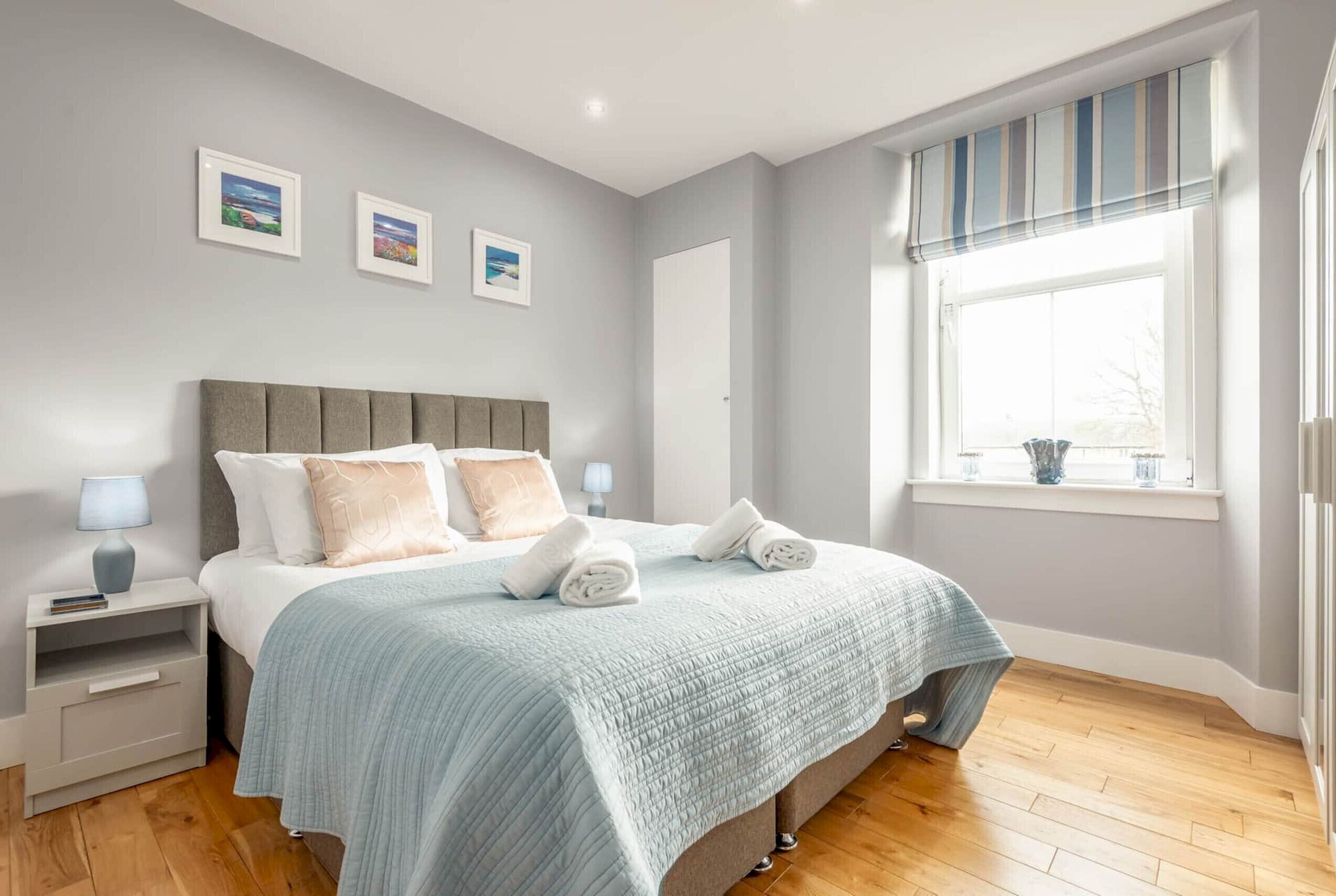 A modern bedroom with a large bed, bedside tables, and a window with a view.