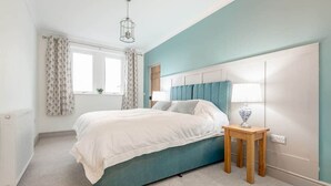 Une chambre à coucher avec un lit, une table de chevet, une lampe et une fenêtre avec des rideaux.