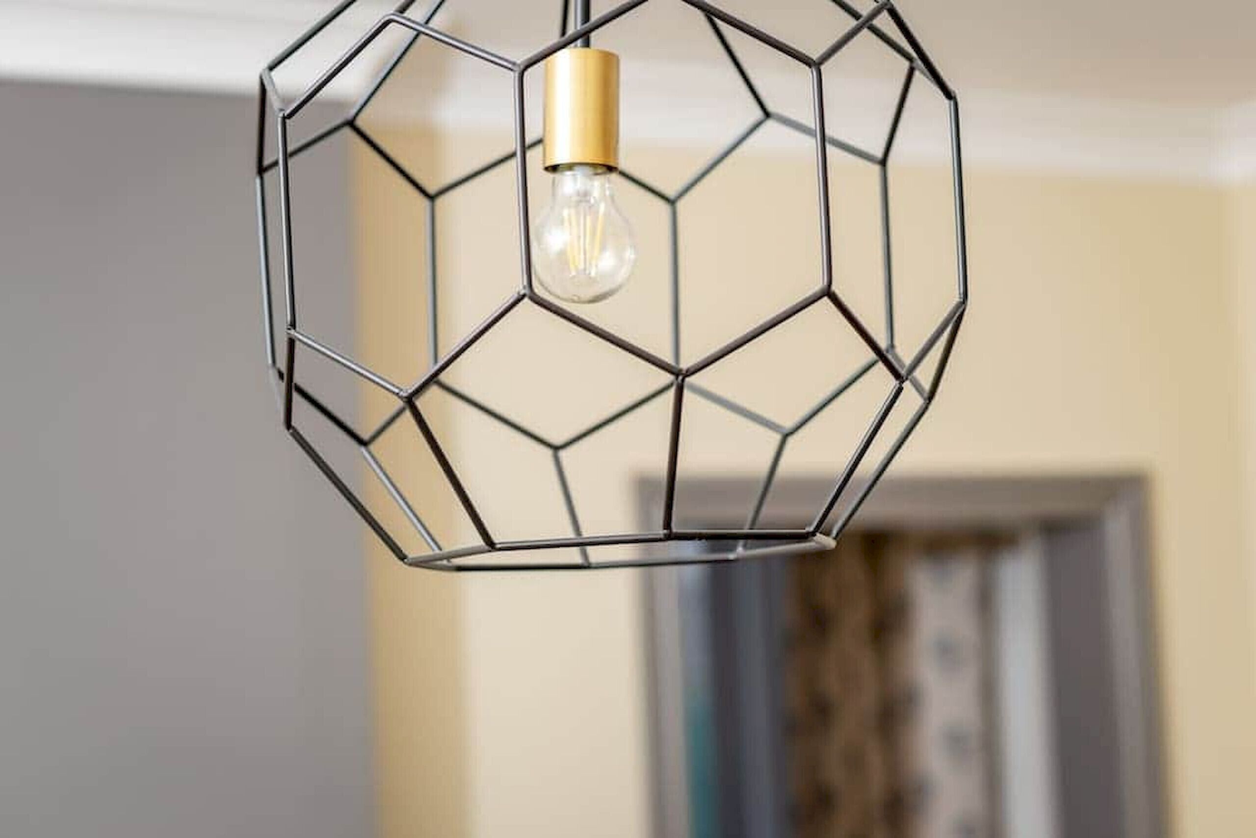 Un luminaire métallique à six faces, avec une ampoule visible.
