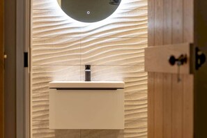 A modern bathroom with a minimalist sink and a unique textured wall. - Firthview | Crail (Anstruther)