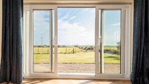 A room with a large sliding glass door leading to an outdoor area with a view of a grassy field and a fence.