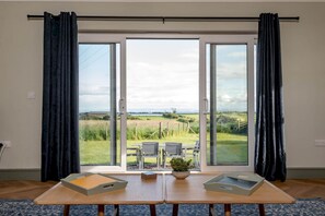 A room with a large sliding glass door leading to an outdoor patio with a table and chairs.