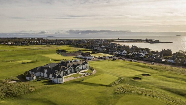 Un campo de golf con un club de campo, una casa grande y vistas al mar.