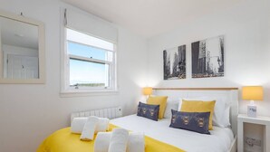 Una habitación de hotel con una cama, dos lámparas de noche, una ventana y una obra de arte en la pared.