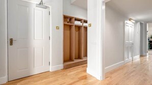 A hallway with wooden flooring, white walls, and a built-in closet with shelves. - Greyfriars Bothy (St Andrews)