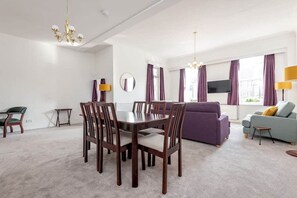 A modern living room with a dining table, chairs, sofas, and a TV. - The Cross Keys Apartment (85D Market Street) (St Andrews)