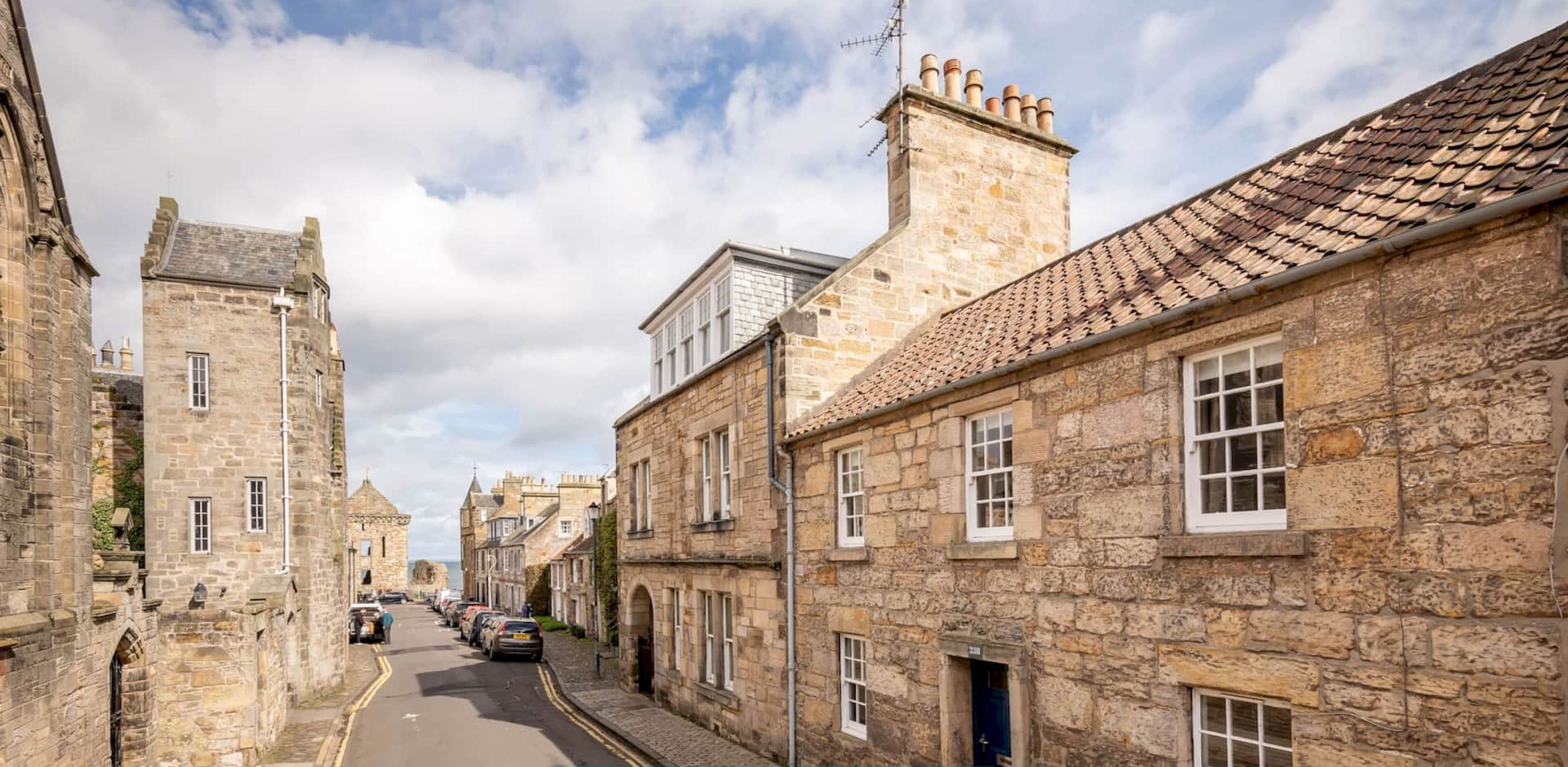 A narrow street lined with stone buildings, some with visible chimneys and windows.