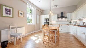 Een moderne keuken met witte kasten, een houten eettafel en een zwarte afzuigkap.