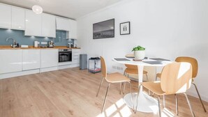 Een moderne keuken met witte kasten, een eettafel met vier stoelen en een kleine potplant.