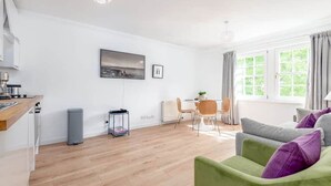 Een moderne woonkamer met een eethoek, een keuken en een groot raam met gordijnen.