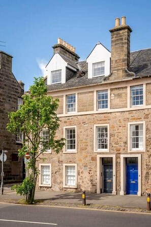 A stone building with multiple windows and a blue door, likely a hotel or historic building.