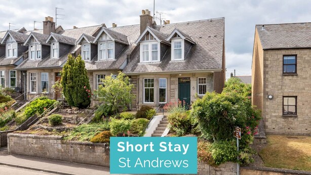 Une rangée de maisons mitoyennes avec une enseigne indiquant « Séjour de courte durée à St Andrews ».
