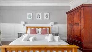 A hotel room with a wooden bed, white bedding, a wooden wardrobe, and three framed wall art pieces. - The Doctor's House (St Andrews)