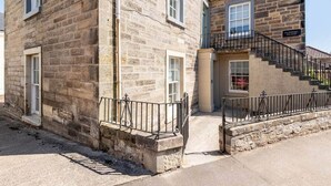 A stone building with a staircase leading to a balcony. - The Doctor's House (St Andrews)