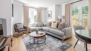 A modern living room with a sectional sofa, a round coffee table, and a TV. - Abbey Villa (No 6) (St Andrews)