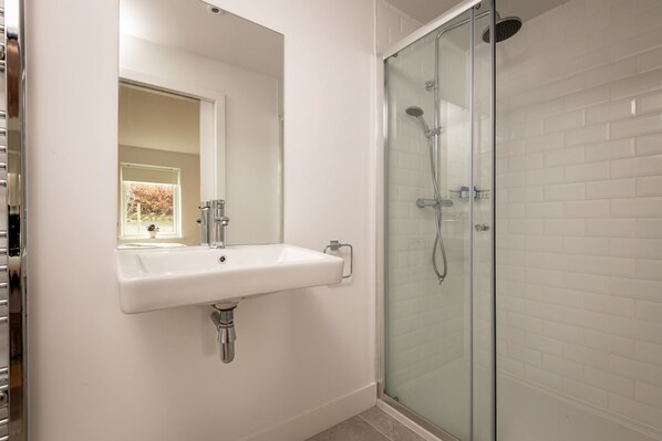 A bathroom with a white sink, a glass shower enclosure, and a mirror above the sink.