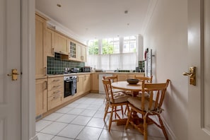 A kitchen with wooden cabinets, a dining table with chairs, and a window providing natural light.