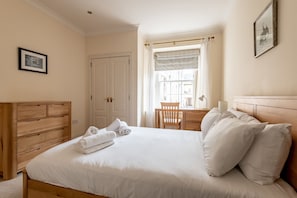 A bedroom with a wooden bed, a desk, and a chair.