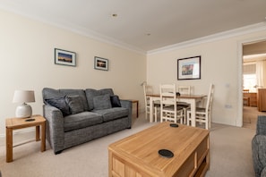 A living room with a grey sofa, wooden coffee table, and framed pictures on the wall.