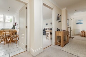 A spacious living area with a dining table and chairs, a wooden side table, and a view into a dining room.