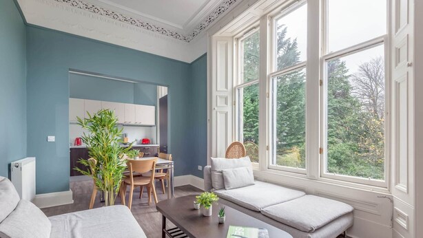 A modern living room with a sofa, a coffee table, and a view of the outdoors. - Queen's Gardens (No 18B) (St Andrews)