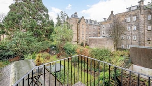 A courtyard with a stone staircase, a large tree, and historic buildings with multiple windows and a dome. - Queen's Gardens (No 18B) (St Andrews)