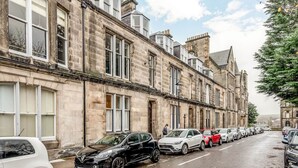 A row of stone buildings with parked cars along a street. - Queen's Gardens (No 18B) (St Andrews)