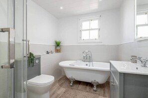 Un baño moderno con una bañera independiente, un inodoro y una cabina de ducha de vidrio.