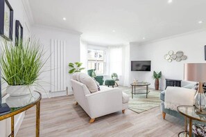 Una sala de estar moderna con un sofá blanco, un sillón verde y una mesa de centro.