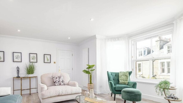 Een woonkamer met een bank, fauteuil en een bijzettafeltje met planten.
