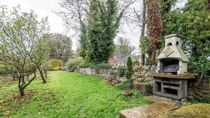 A garden with a stone wall, a stone bench, and a stone structure resembling a fireplace. - Park Mill Cottages | Mill Cottage (St Andrews)